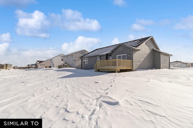 snow covered rear of property featuring a deck