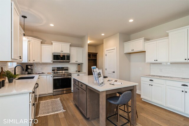 kitchen featuring a center island, white cabinets, sink, light wood-type flooring, and appliances with stainless steel finishes