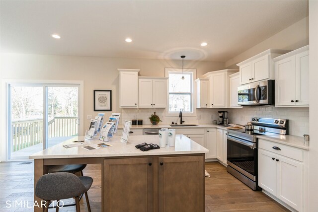 kitchen featuring a wealth of natural light, a kitchen island, hanging light fixtures, and appliances with stainless steel finishes