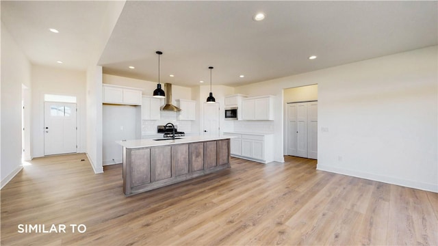 kitchen featuring white cabinets, light hardwood / wood-style floors, a kitchen island with sink, and sink