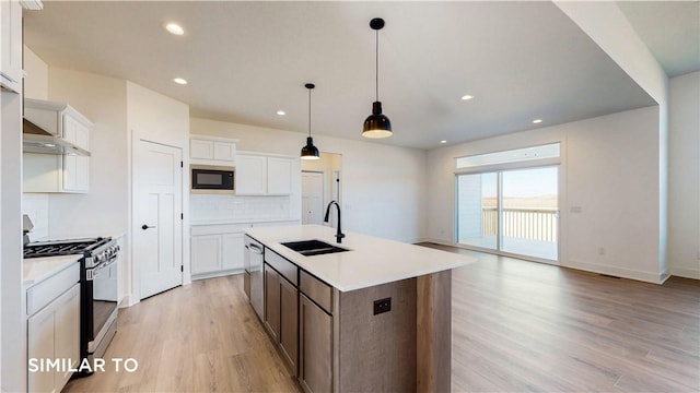 kitchen with a center island with sink, white cabinets, sink, and appliances with stainless steel finishes