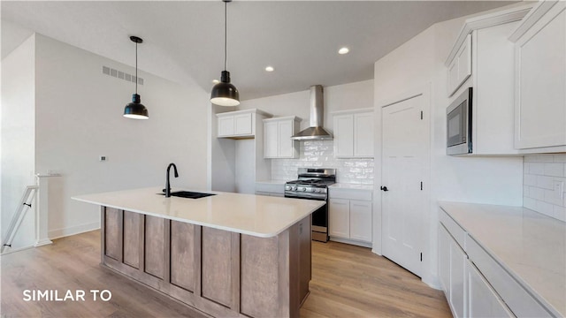 kitchen featuring backsplash, sink, wall chimney exhaust hood, white cabinetry, and stainless steel appliances