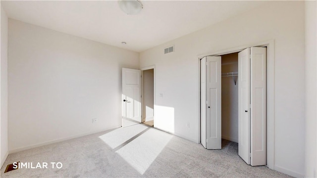 unfurnished bedroom with light carpet and a closet