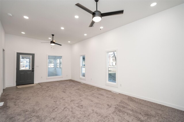 unfurnished living room featuring carpet flooring, ceiling fan, and a wealth of natural light