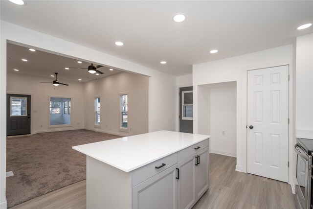 kitchen featuring ceiling fan, a center island, stainless steel electric range, and light wood-type flooring