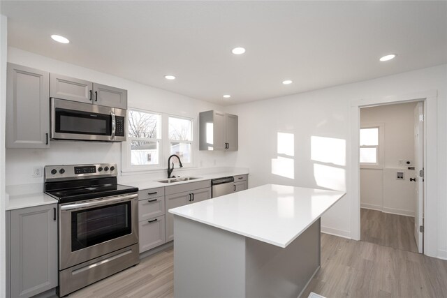 kitchen featuring stainless steel appliances, light hardwood / wood-style flooring, gray cabinetry, and sink