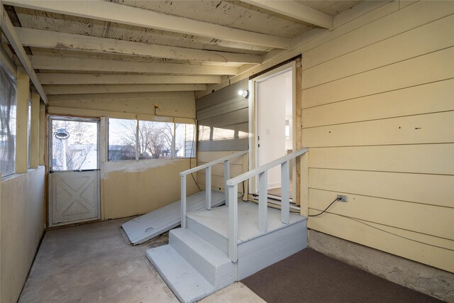 stairs with wood walls, concrete floors, and vaulted ceiling