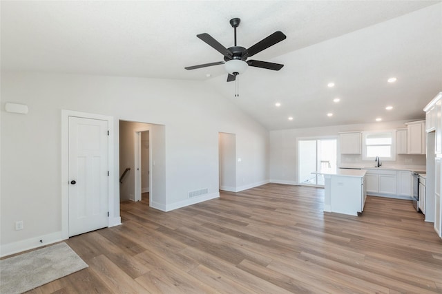 kitchen with light countertops, open floor plan, white cabinetry, a kitchen island, and light wood-type flooring