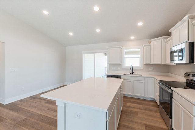 kitchen with a sink, a kitchen island, white cabinetry, light countertops, and appliances with stainless steel finishes