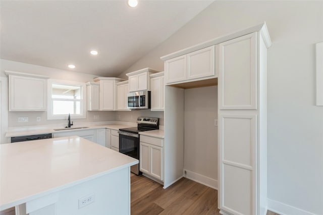 kitchen with lofted ceiling, light countertops, appliances with stainless steel finishes, white cabinetry, and a sink