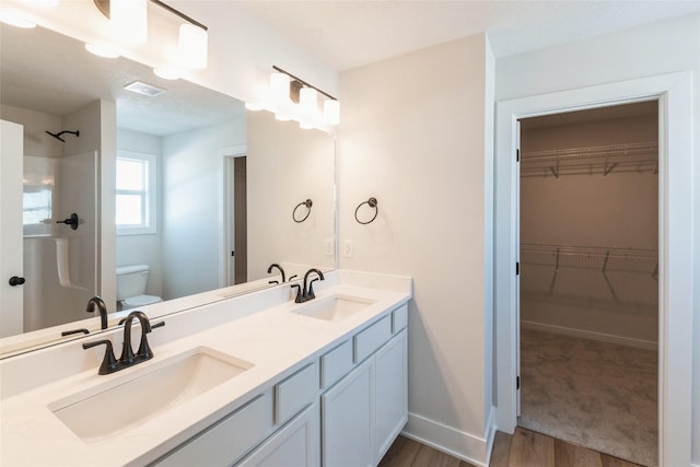 bathroom with visible vents, a spacious closet, a sink, and toilet