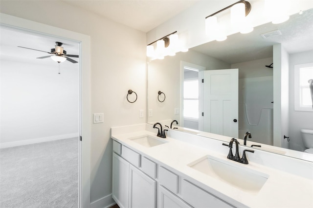 bathroom featuring baseboards, a sink, toilet, and double vanity