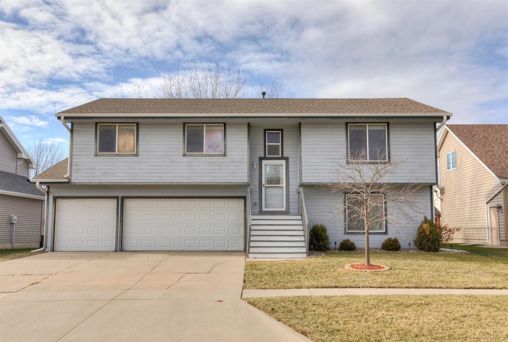 raised ranch with a garage and a front lawn