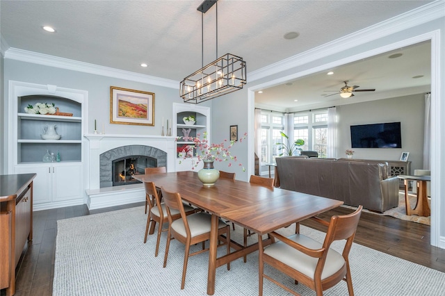 dining area with built in features, a fireplace, crown molding, and dark hardwood / wood-style floors