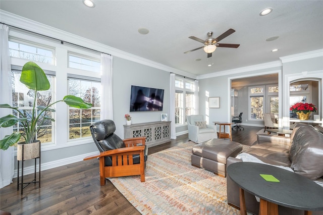 living room with dark wood-type flooring, crown molding, ceiling fan, and a healthy amount of sunlight