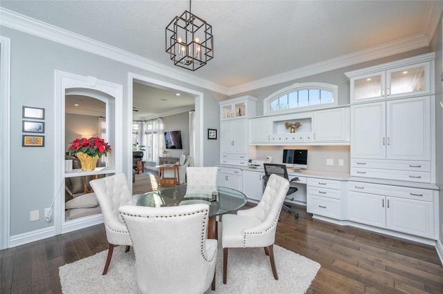 dining area with a notable chandelier, crown molding, built in desk, and dark wood-type flooring