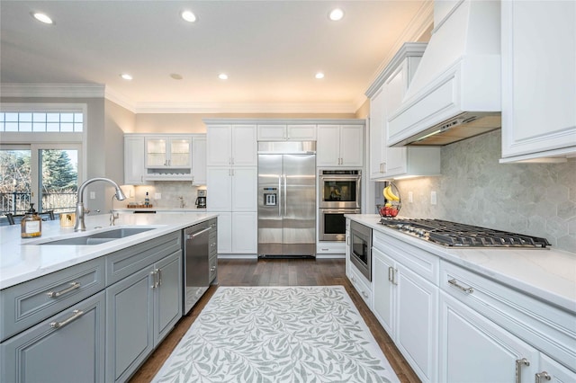 kitchen with custom range hood, sink, built in appliances, dark hardwood / wood-style floors, and white cabinetry