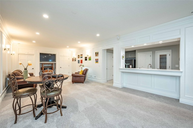 carpeted dining area featuring sink and crown molding