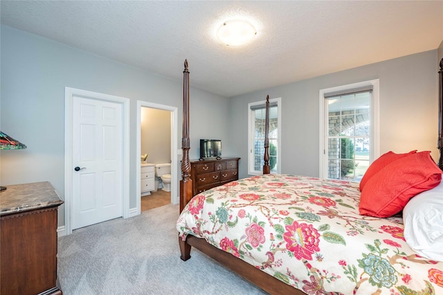 carpeted bedroom with a textured ceiling and ensuite bath