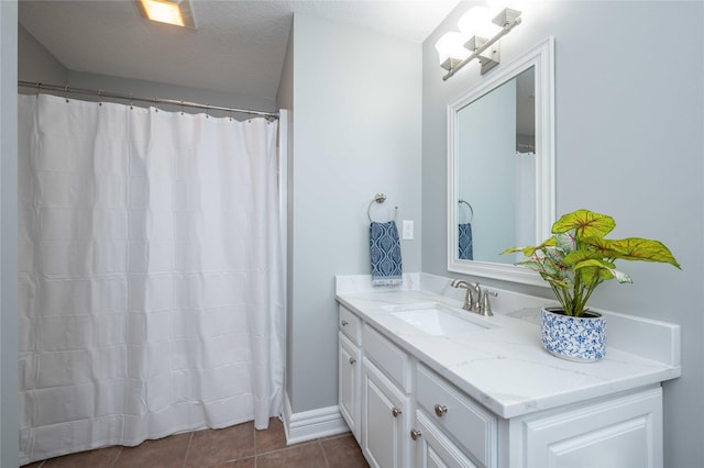 bathroom with tile patterned flooring, vanity, and a textured ceiling