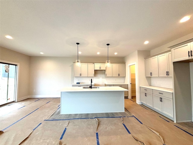 kitchen with hanging light fixtures, a kitchen island with sink, and sink