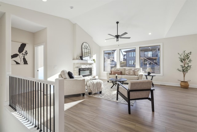 living room with wood finished floors, a fireplace, baseboards, and lofted ceiling