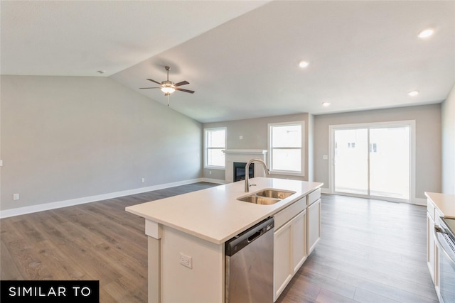 kitchen with stainless steel appliances, sink, light hardwood / wood-style floors, lofted ceiling, and an island with sink