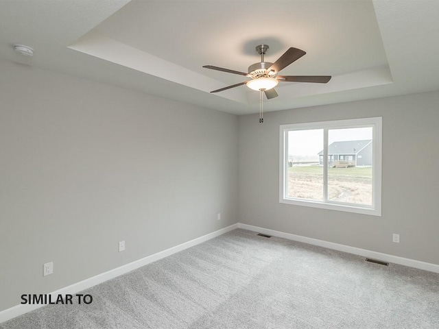 spare room with carpet, ceiling fan, and a tray ceiling