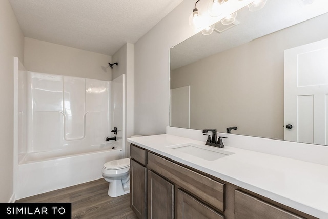 full bathroom with hardwood / wood-style floors, vanity, shower / washtub combination, toilet, and a textured ceiling