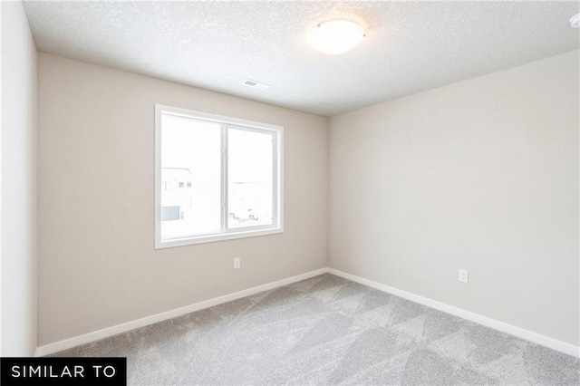 spare room featuring carpet and a textured ceiling