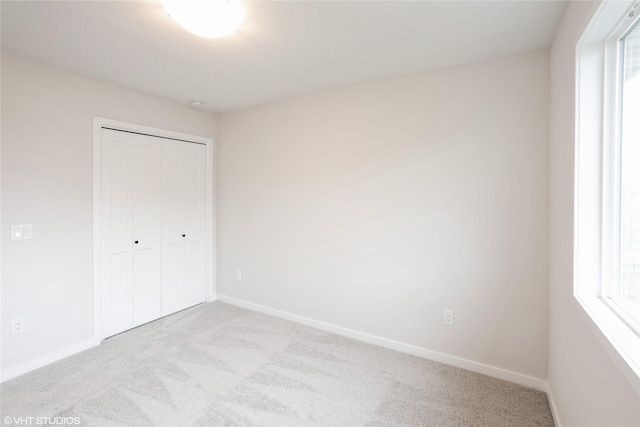 unfurnished bedroom with a closet, multiple windows, carpet floors, and baseboards