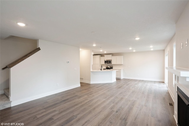unfurnished living room with stairway, wood finished floors, and recessed lighting