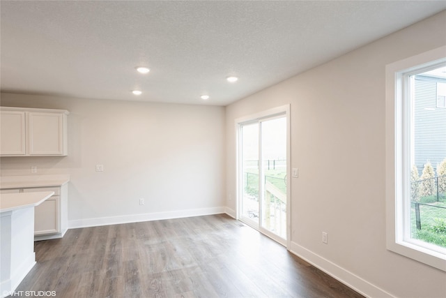 unfurnished living room featuring a textured ceiling, wood finished floors, recessed lighting, and baseboards