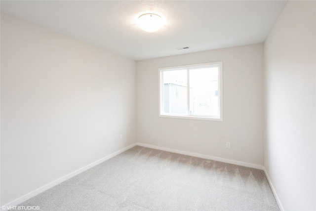 empty room featuring baseboards, visible vents, and light colored carpet