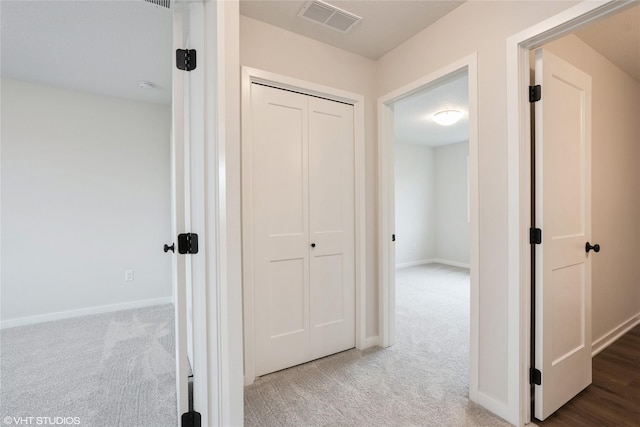 hall with carpet flooring, visible vents, and baseboards