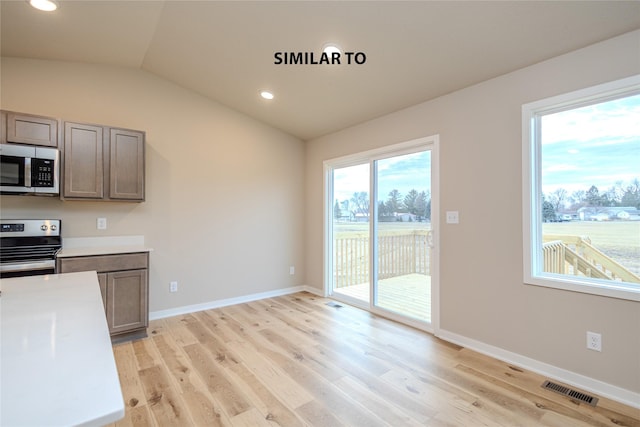 kitchen with light wood-type flooring, lofted ceiling, and appliances with stainless steel finishes