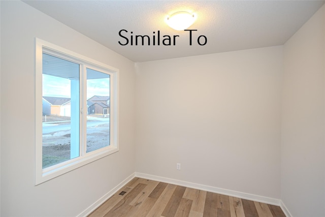 empty room with hardwood / wood-style floors and plenty of natural light