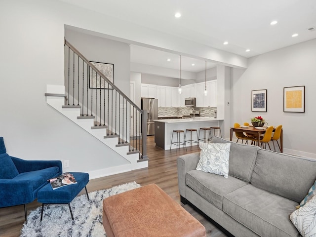 living area with visible vents, baseboards, wood finished floors, stairs, and recessed lighting