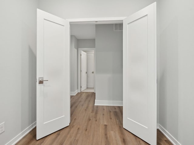 corridor with visible vents, baseboards, and wood finished floors