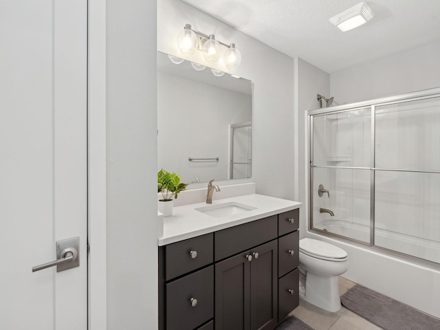 full bath featuring toilet, tile patterned flooring, combined bath / shower with glass door, a textured ceiling, and vanity