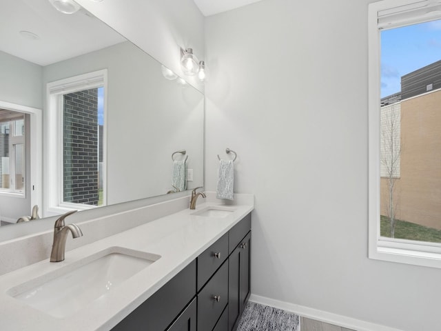 bathroom featuring double vanity, baseboards, and a sink