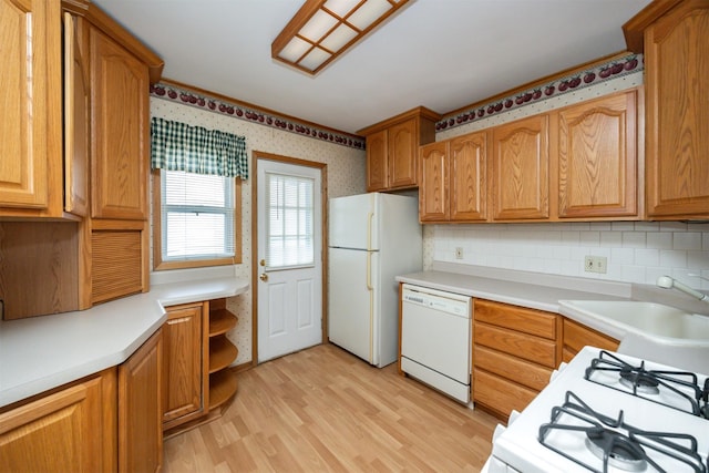 kitchen featuring sink, white appliances, light hardwood / wood-style flooring, and backsplash