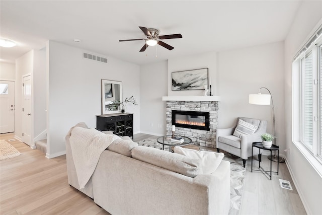 living room featuring ceiling fan, a fireplace, and light hardwood / wood-style floors