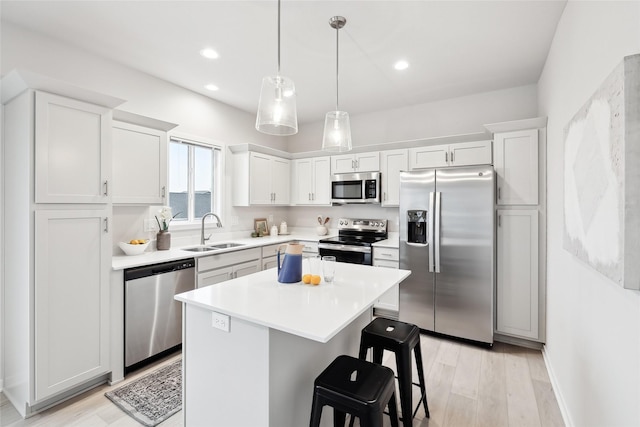 kitchen featuring appliances with stainless steel finishes, a breakfast bar, sink, white cabinets, and a center island