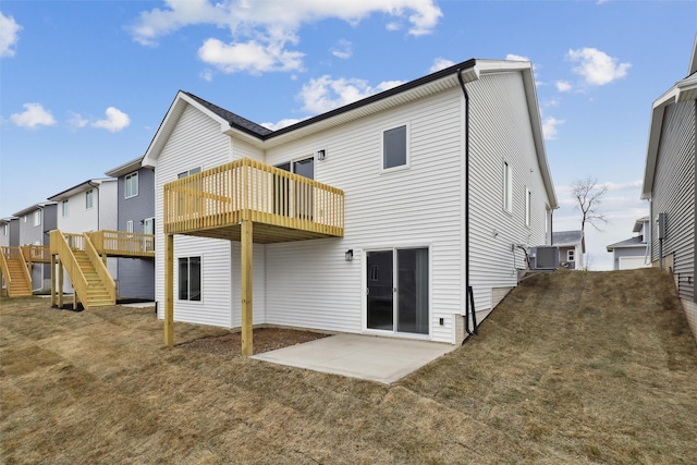 rear view of property featuring a lawn, a deck, and a patio