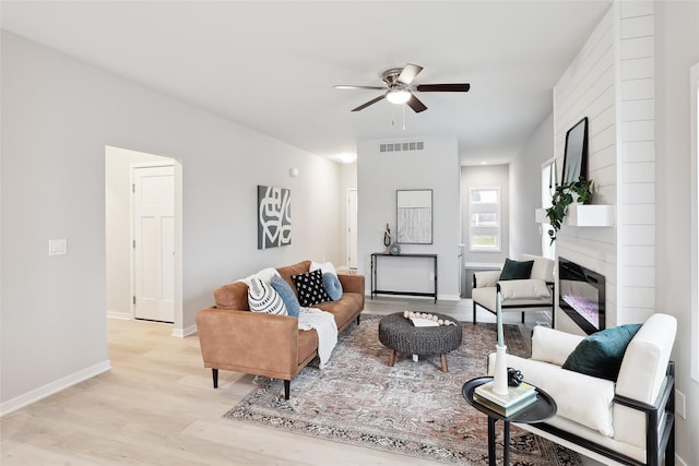 living room with a fireplace, light hardwood / wood-style flooring, and ceiling fan