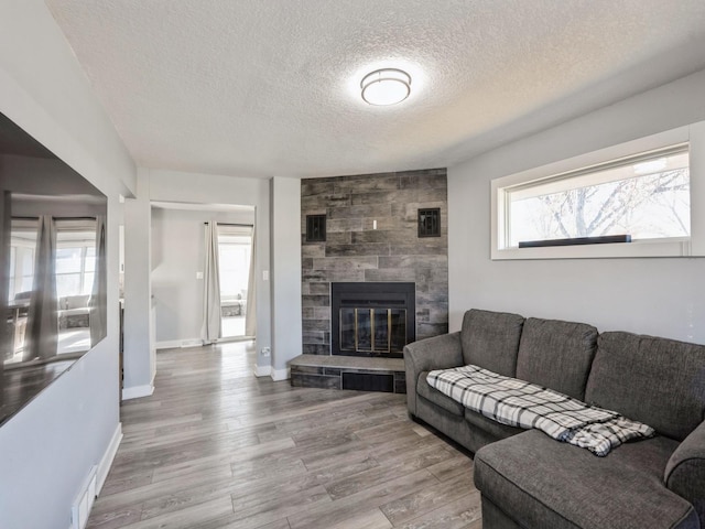 living room featuring a fireplace, a textured ceiling, and light hardwood / wood-style floors