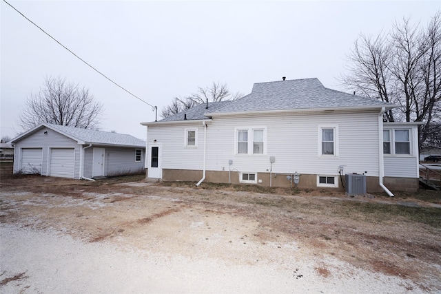 back of house with cooling unit, a garage, and an outbuilding