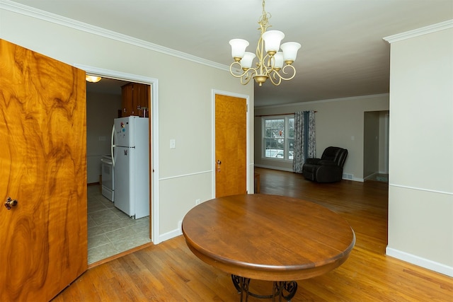 dining room with a chandelier, crown molding, and light hardwood / wood-style floors