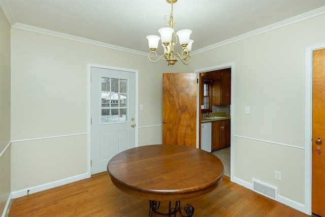 dining space featuring light hardwood / wood-style floors, ornamental molding, and an inviting chandelier